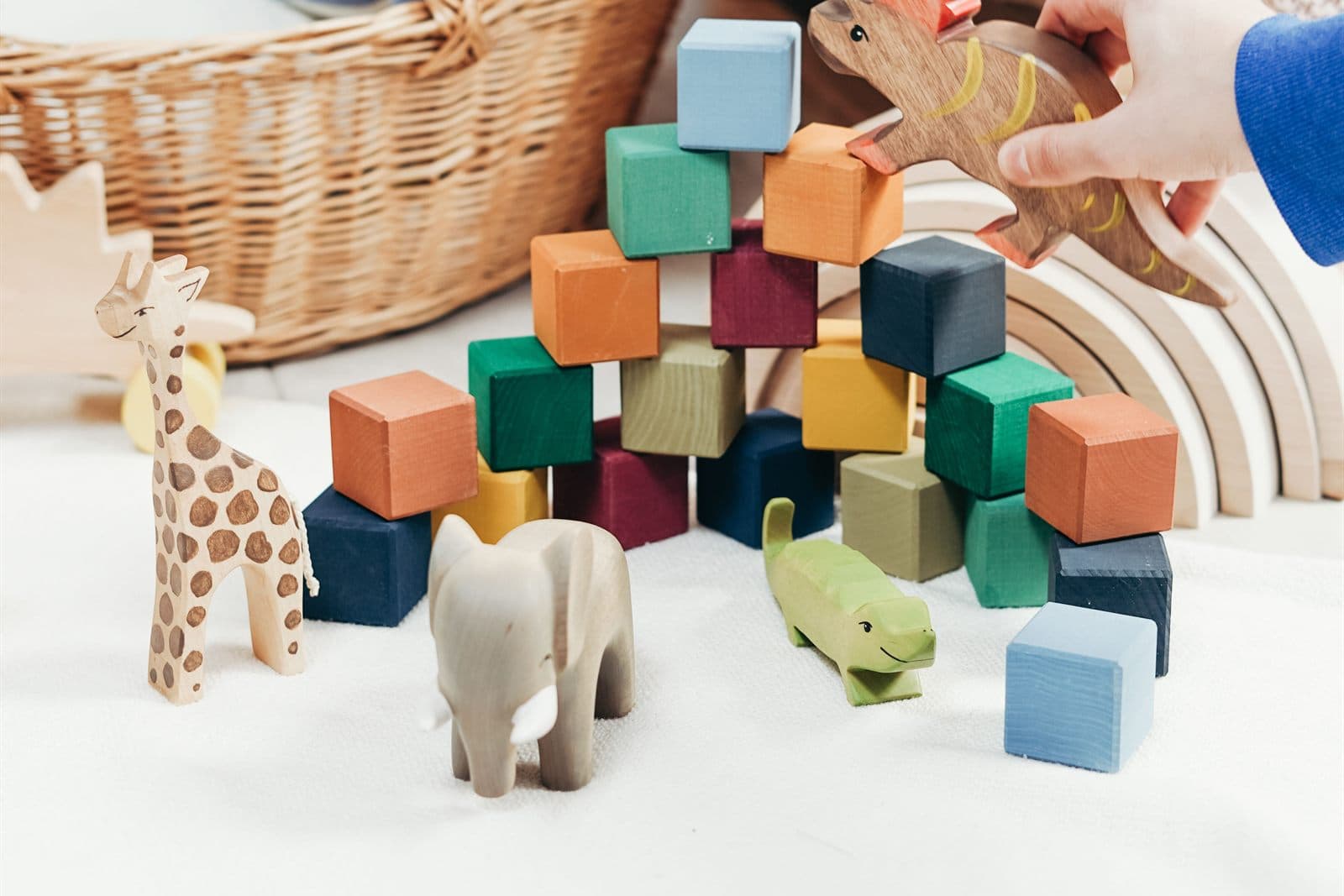 Des jouets en bois, des cubes colorés et les mains d'un enfant qui joue